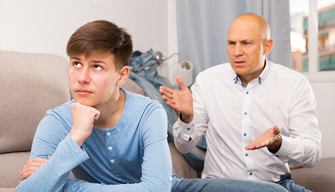 Photo d'un père qui discute avec son fils qui ne veut pas l'écouter